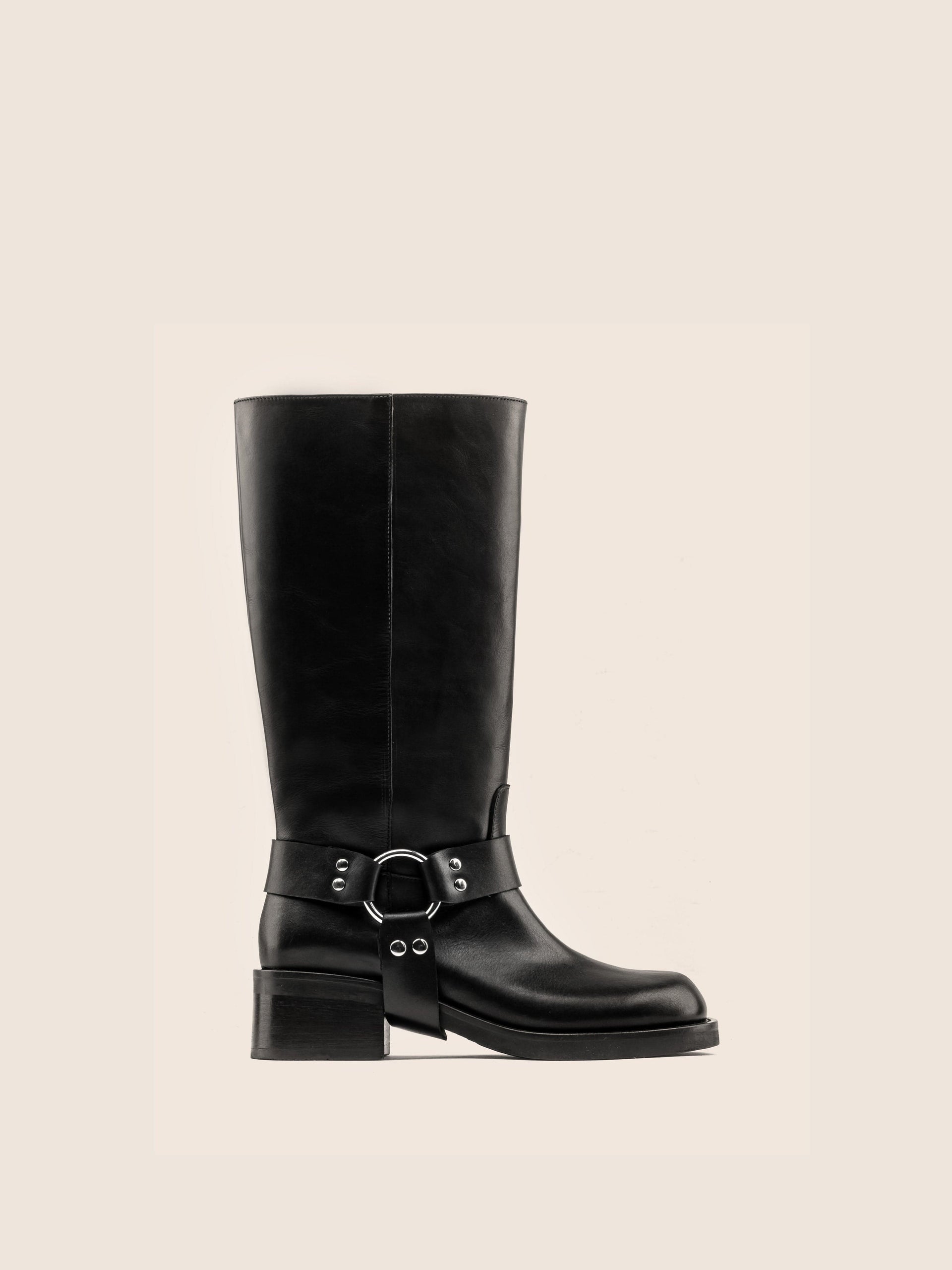 A black leather boot with a harness detail and block heel, on a white background.