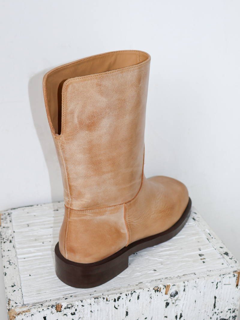 Tan boot on a white surface with a light gray background