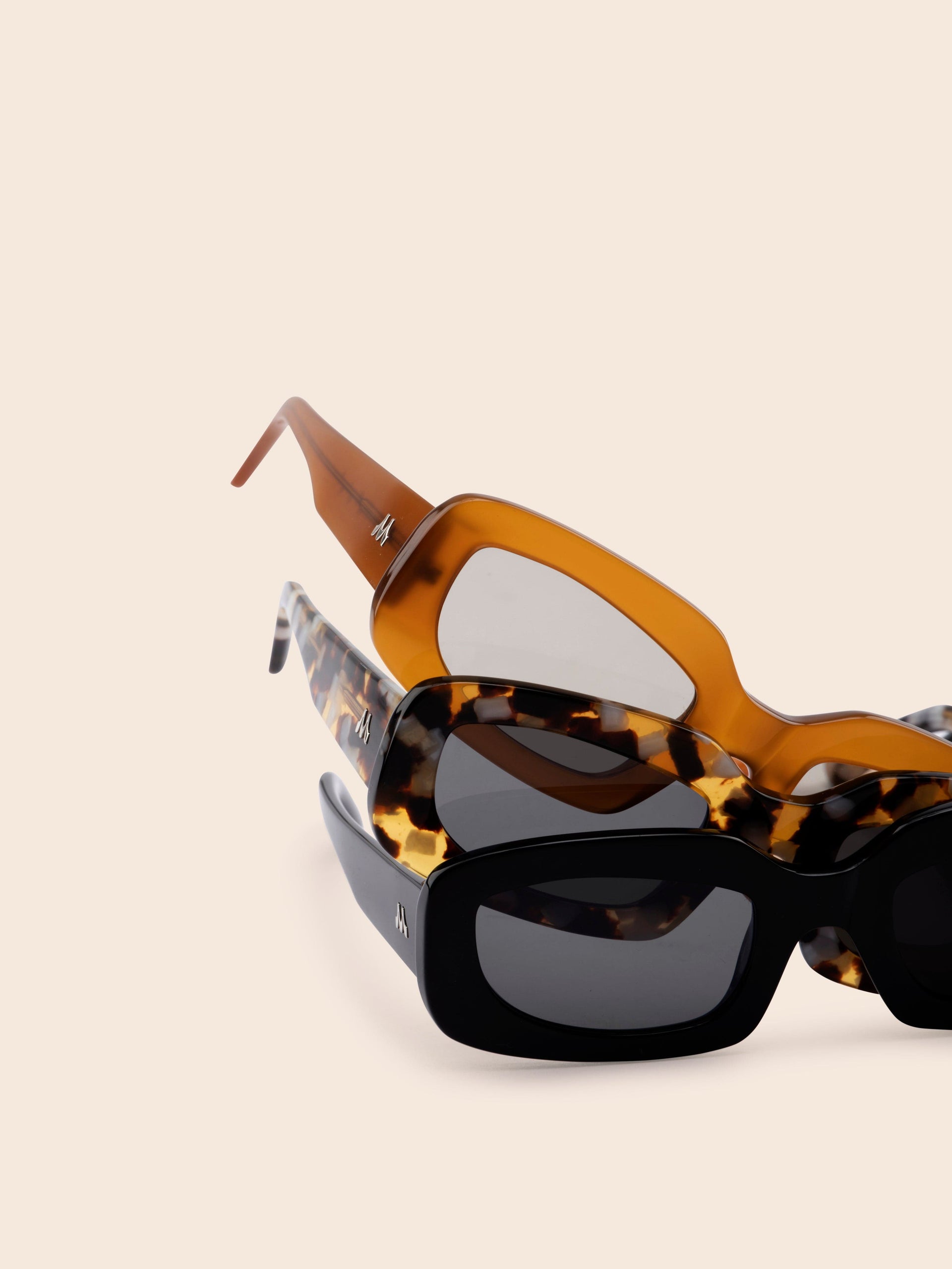 3 sunglasses on top of each other. Black, tortoise and tan