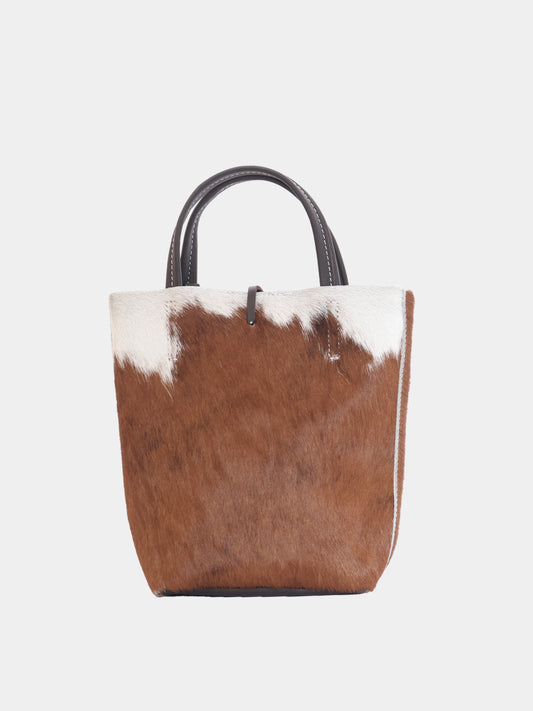 Carpi mini tote bag with cow-print pony hair and brown leather straps, back view.