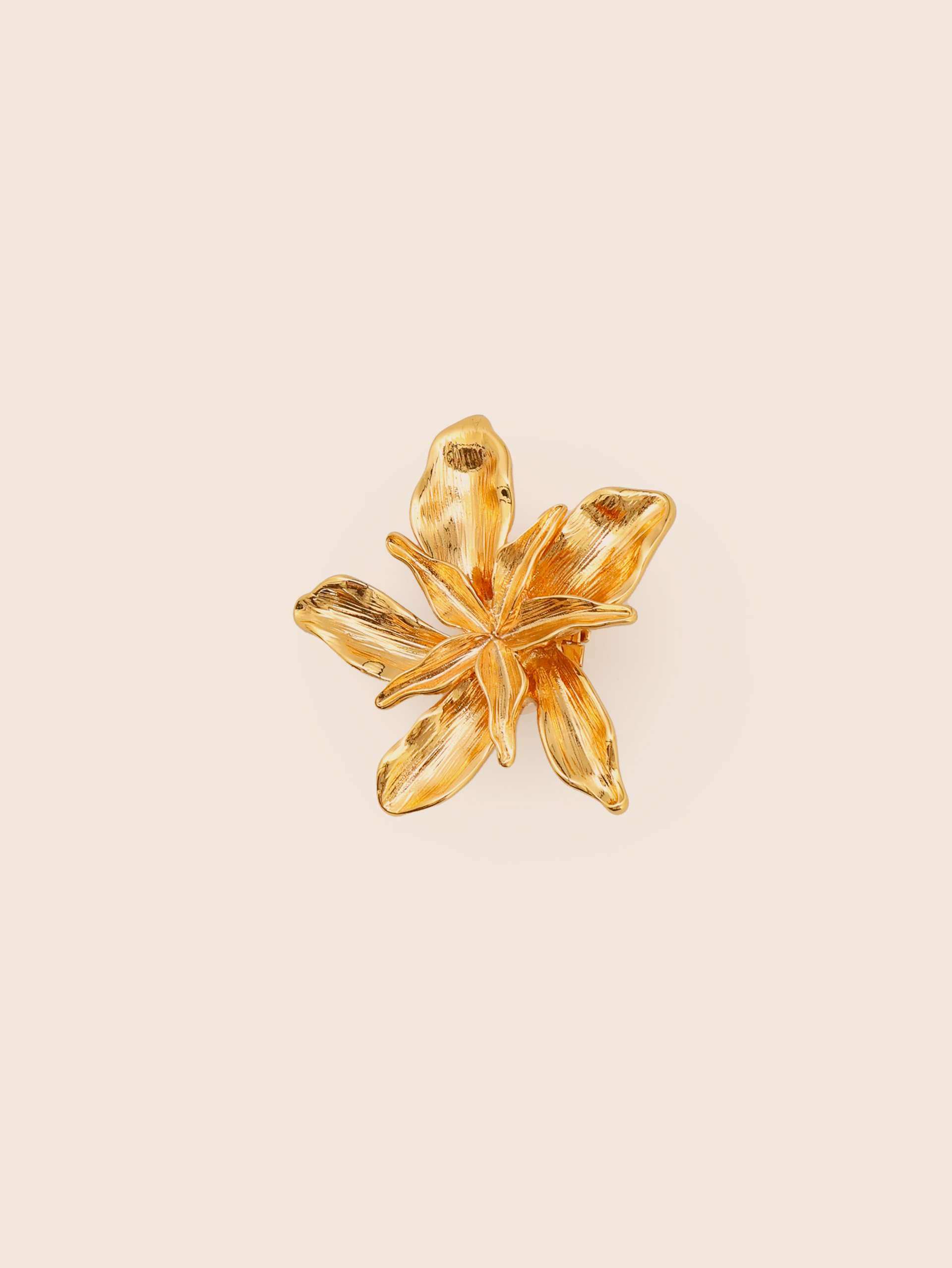 A gold-colored metal hair clip designed to resemble a flower.