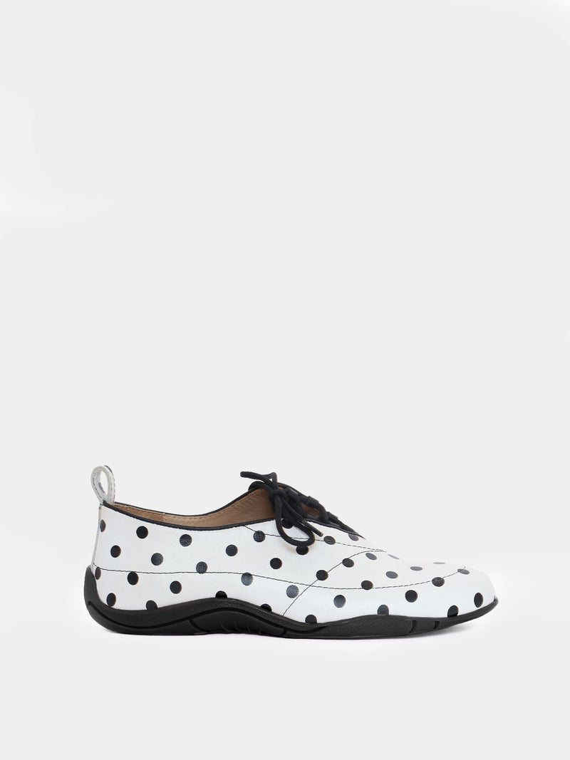 white and black polka dot asymmetrical sneaker on gray background