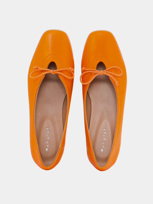 Pair of orange flats with matching laces on a light gray background