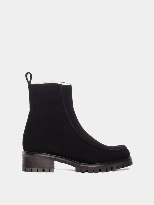 Shearling lined winter boot with a front piping detail, in a black suede with a black lug outsole. 