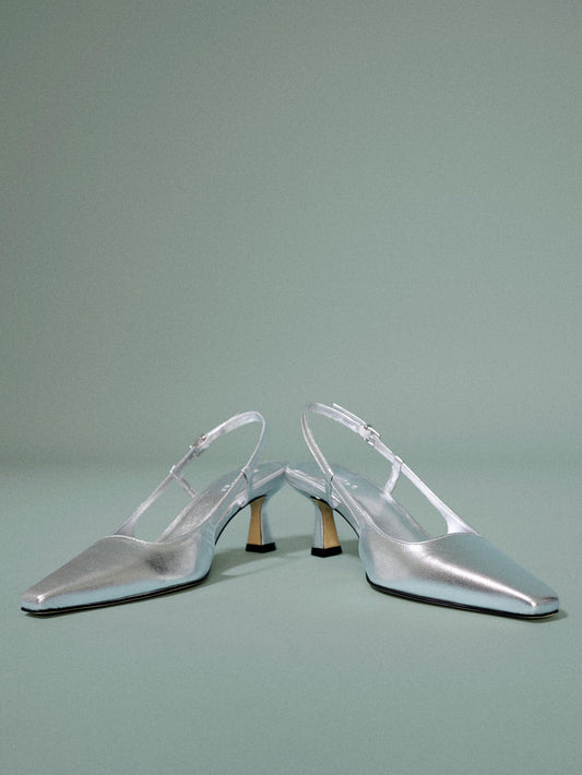 A pair of silver heel on a light blue background