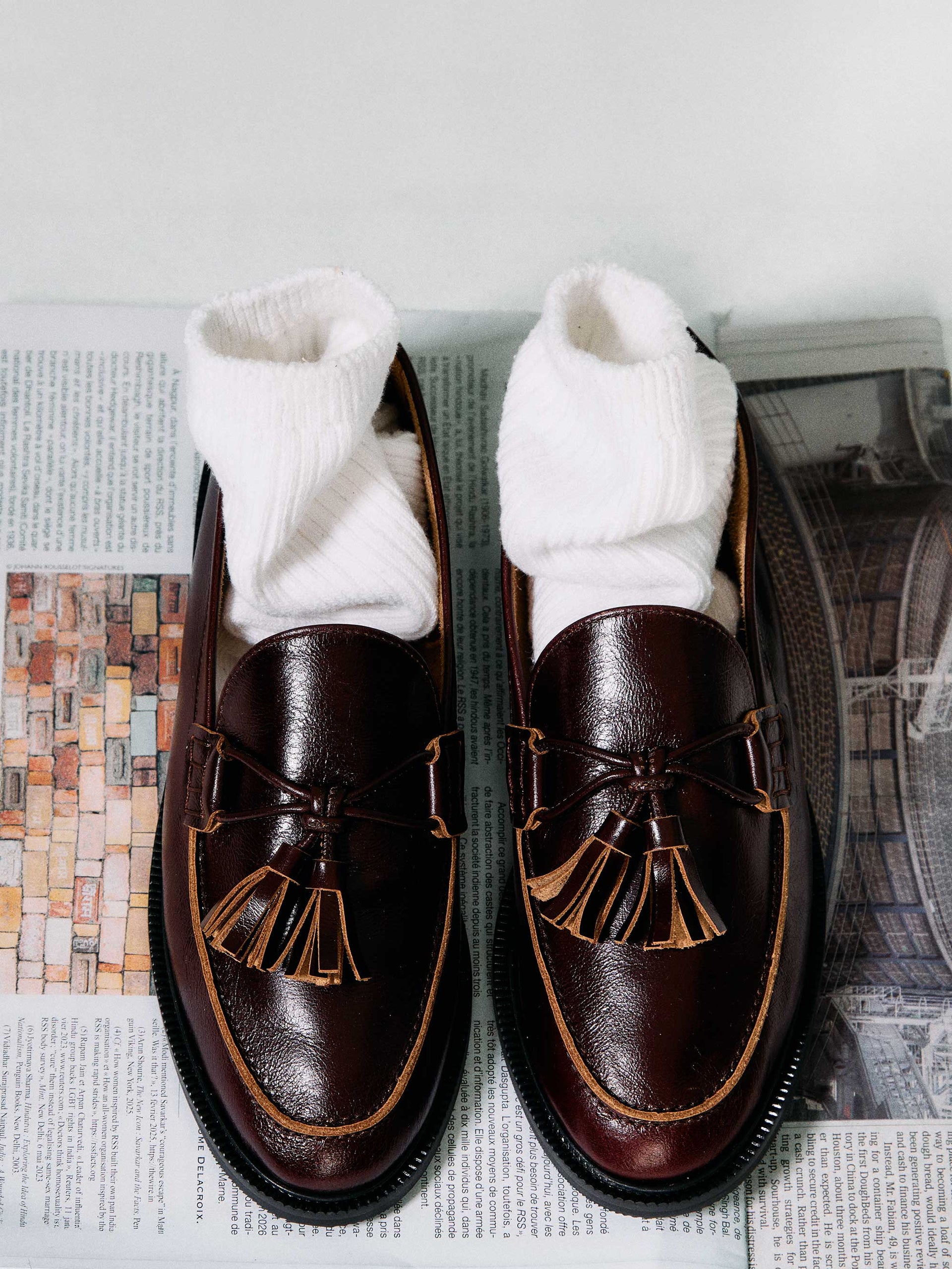 Pair of brown loafers with tassels on a newspaper background