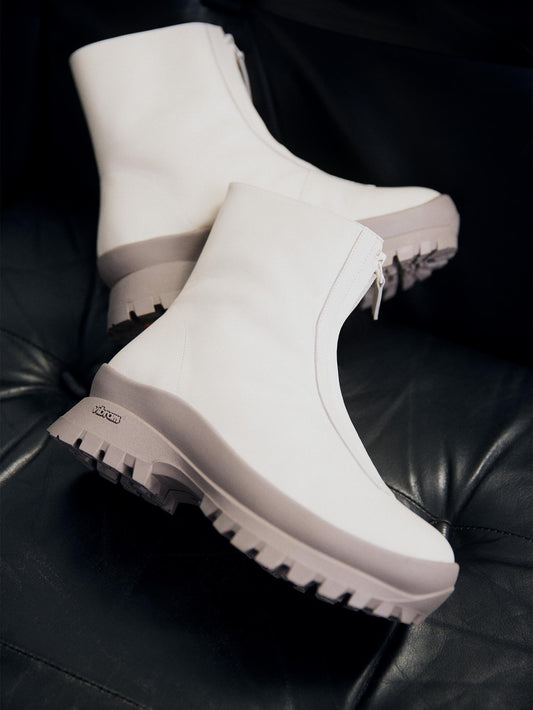 White leather boot with taupe outsole on a black sofa