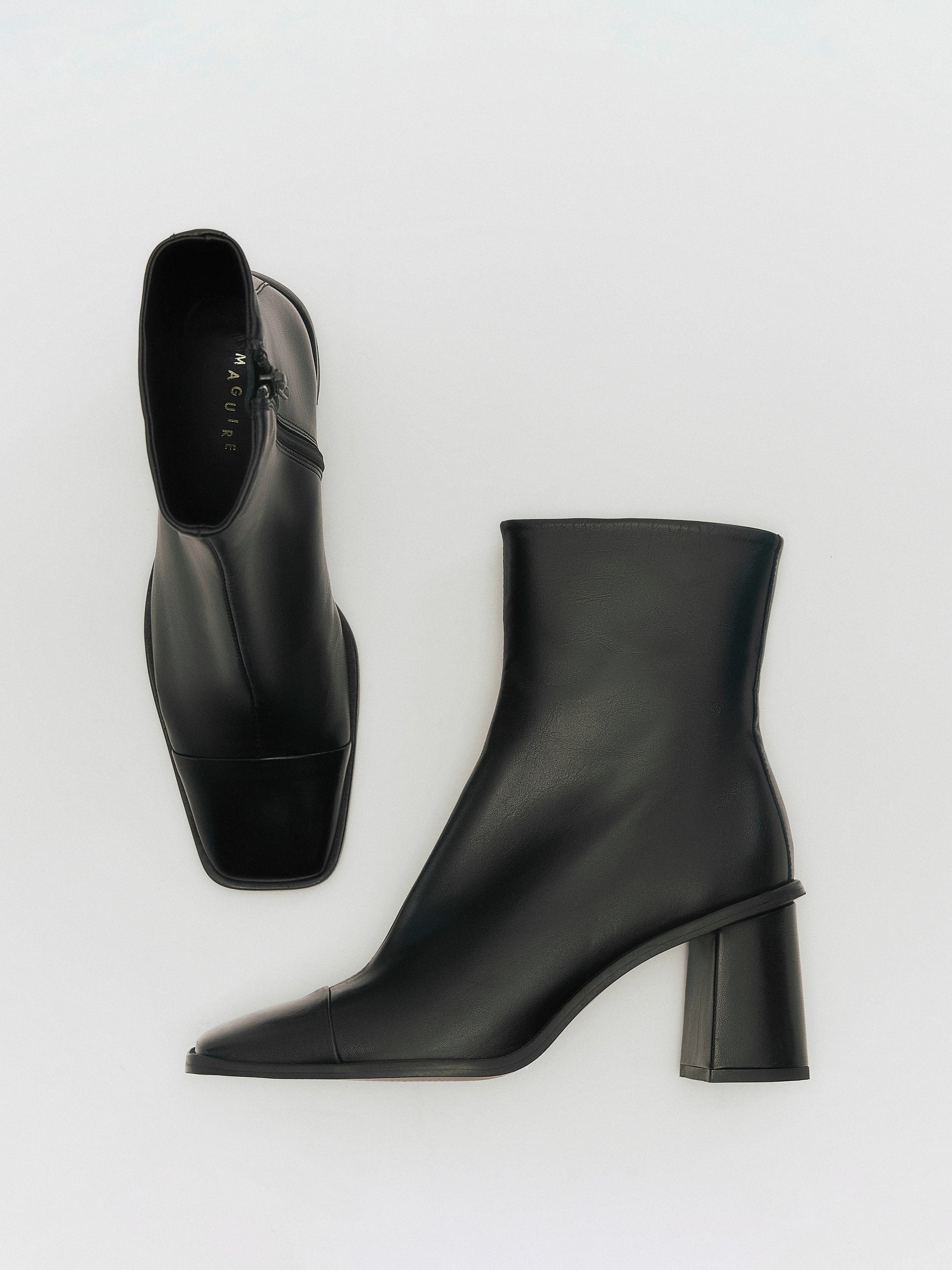 A black heeled boot with a square toe on a white background