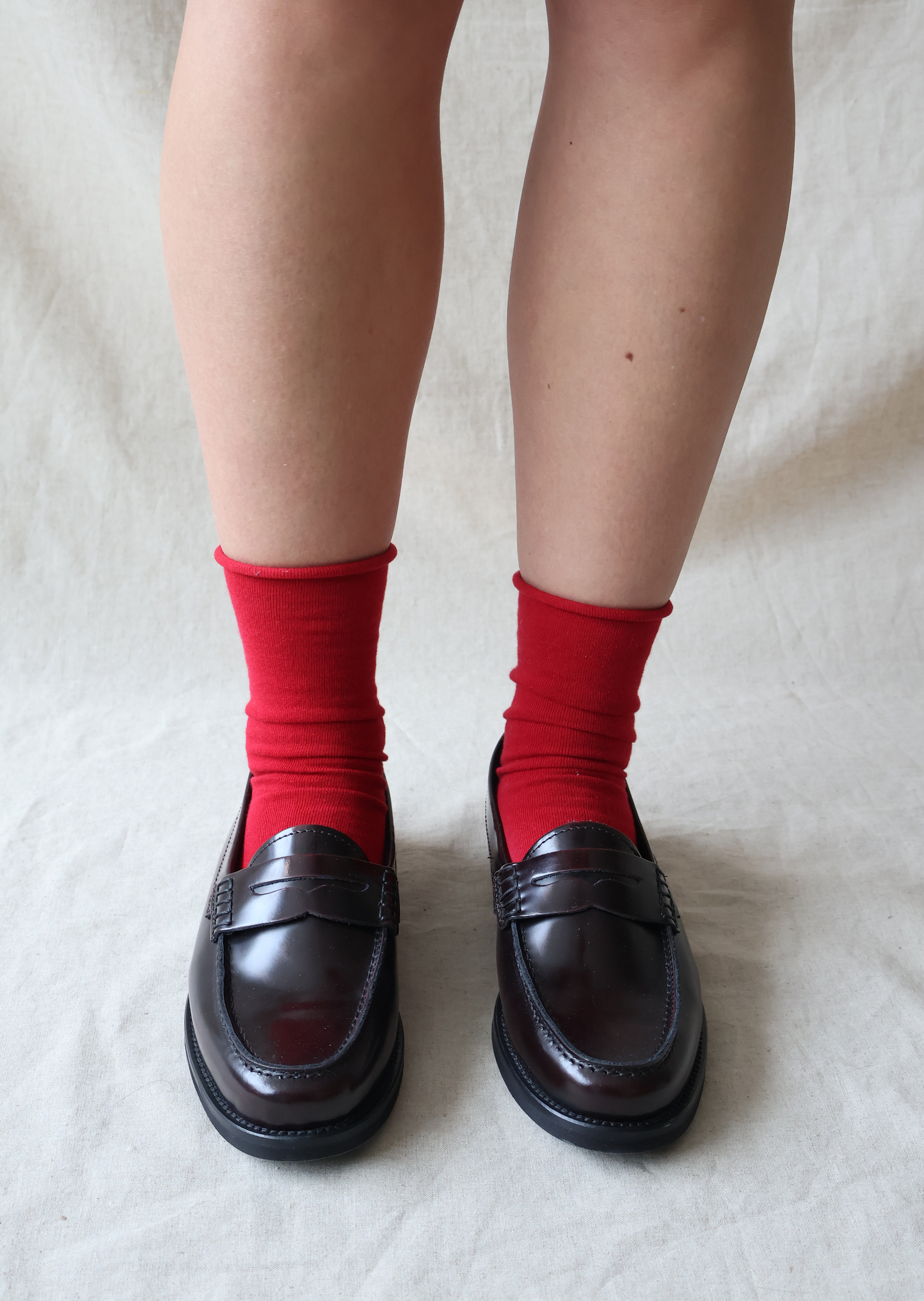Person wearing red socks and black shoes on a light background