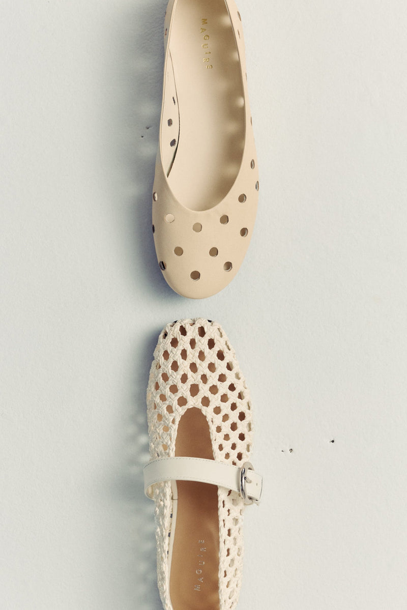 two ballet flats on white floor facing each oter. both leather and cream coloured with perforated details