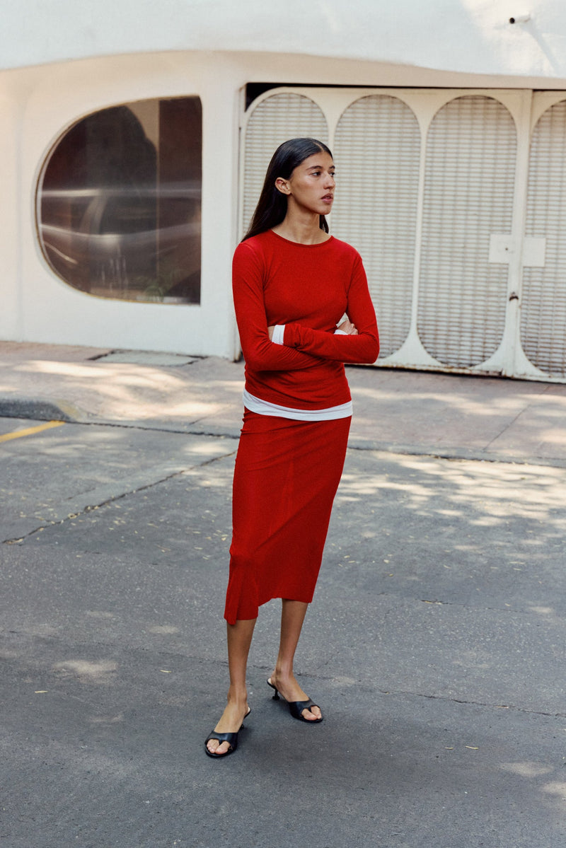 Woman in red outfit standing in black open toe heeled sandal on street corner