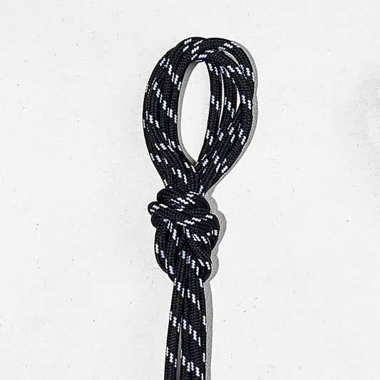 Black and white laces tied in a knot on a light gray background