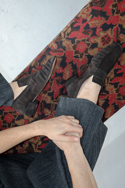 Person wearing dark shoes and gray socks on a patterned rug.