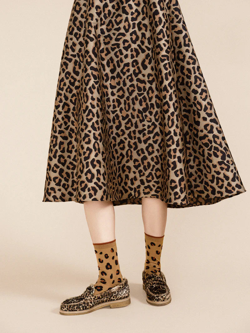 A person wearing animal print espadrilles,skirt and matching cheetah print socks.