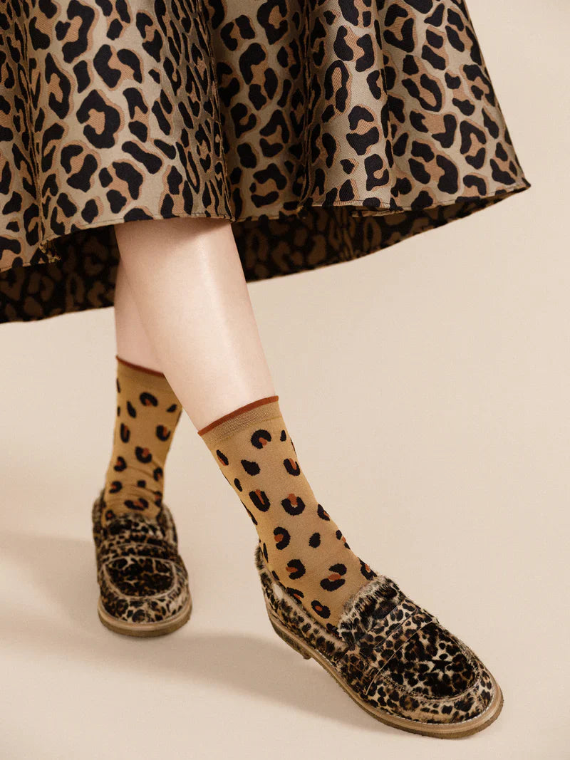 A person wearing animal print espadrilles and matching cheetah print socks.