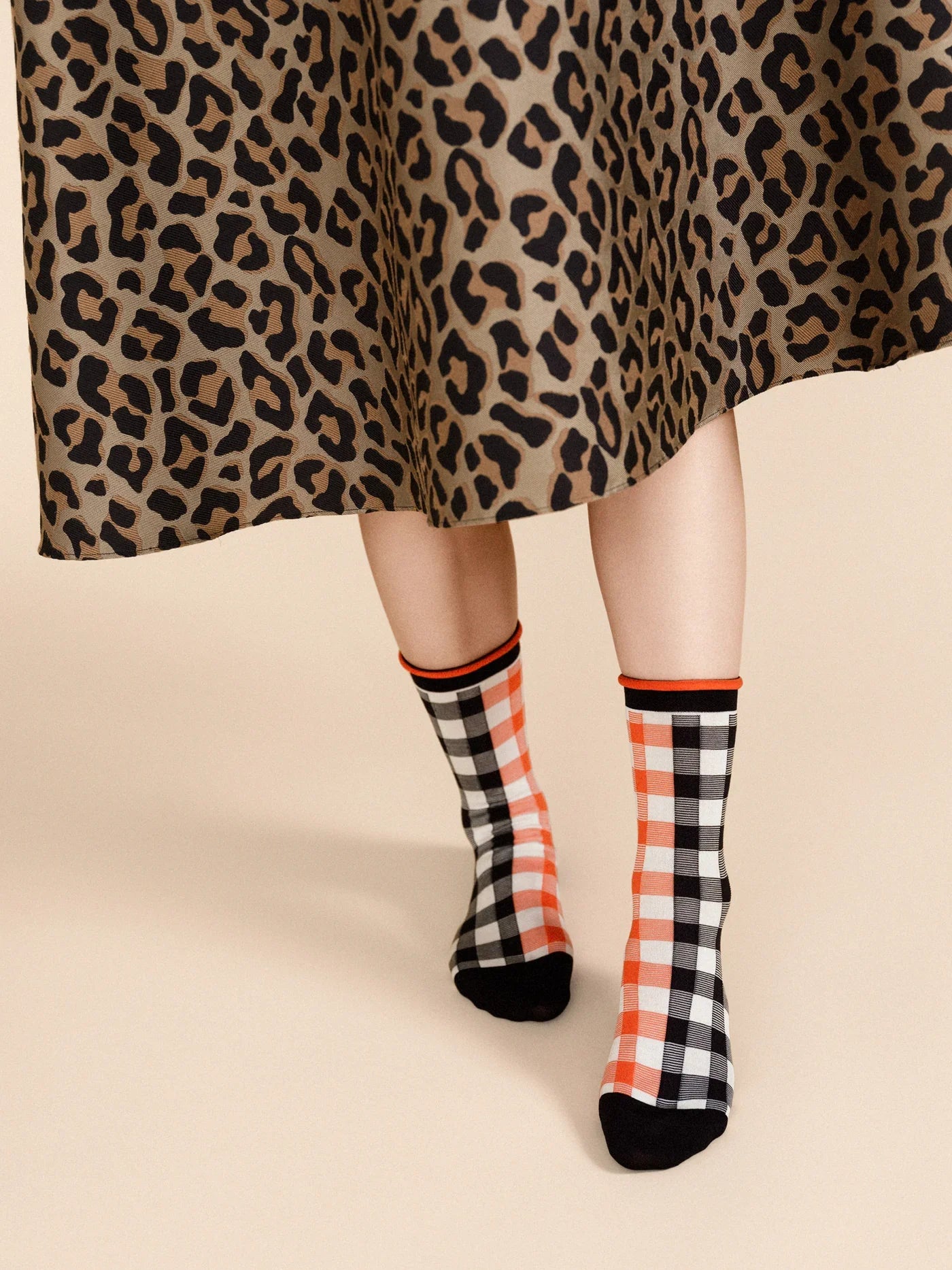 A pair of checkered socks in black, white, and red worn with a leopard print skirt.