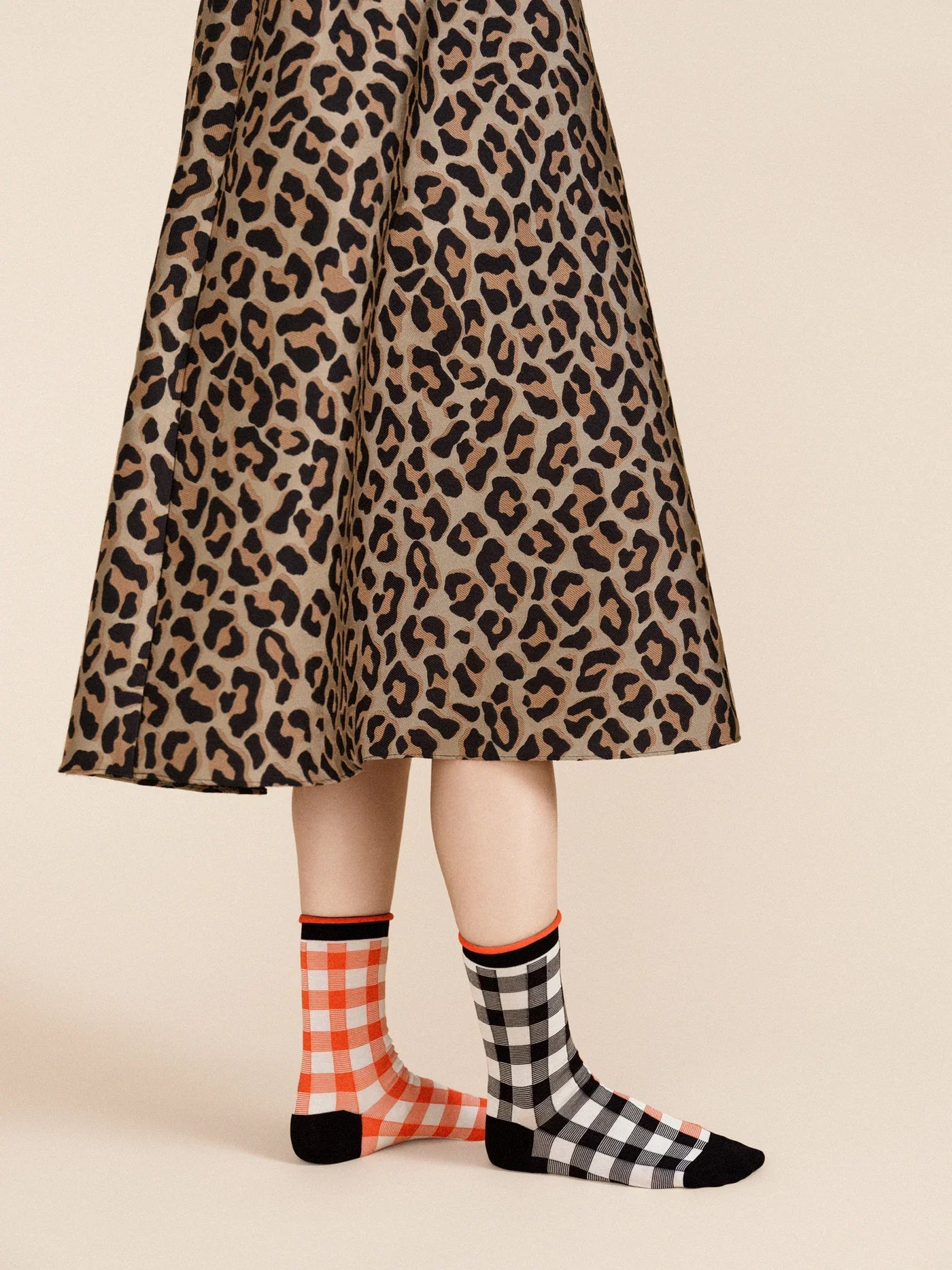 A pair of checkered socks in black, white, and red worn with a leopard print skirt.