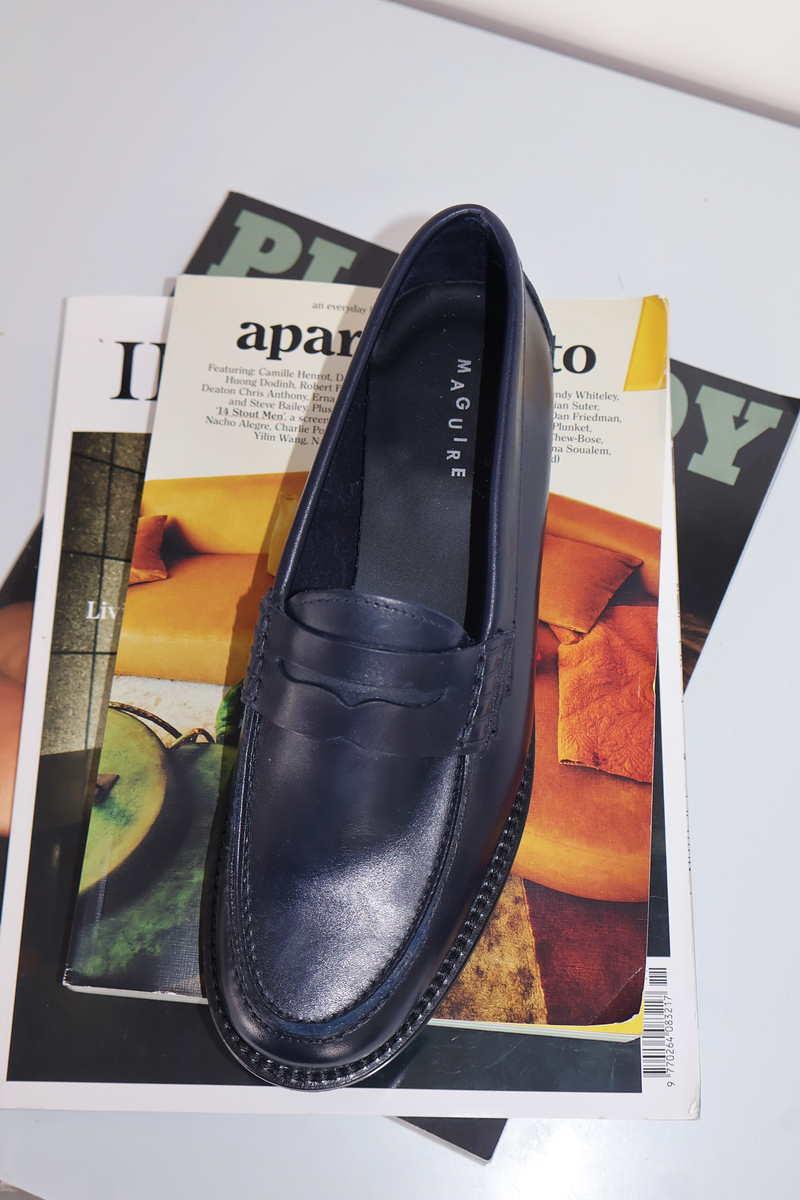 Navy loafer shoe on top of a magazine